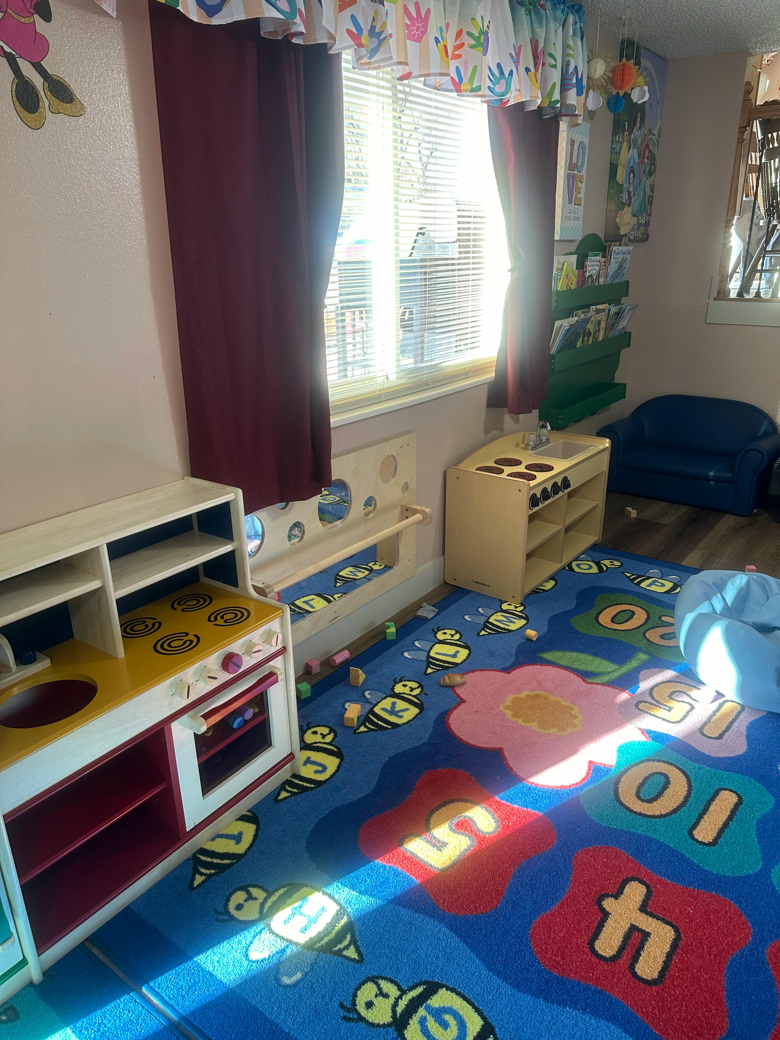 Playroom with toy kitchen, colorful rug, and window