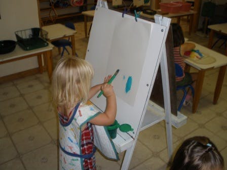 Child painting on an easel in a classroom