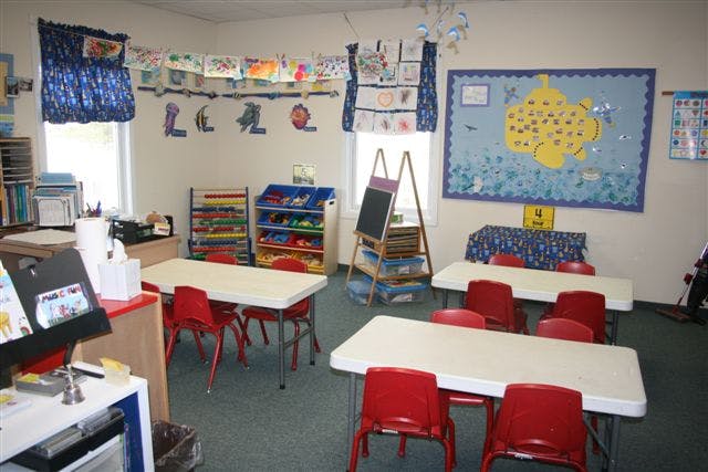 Classroom with small tables and chairs, art on walls