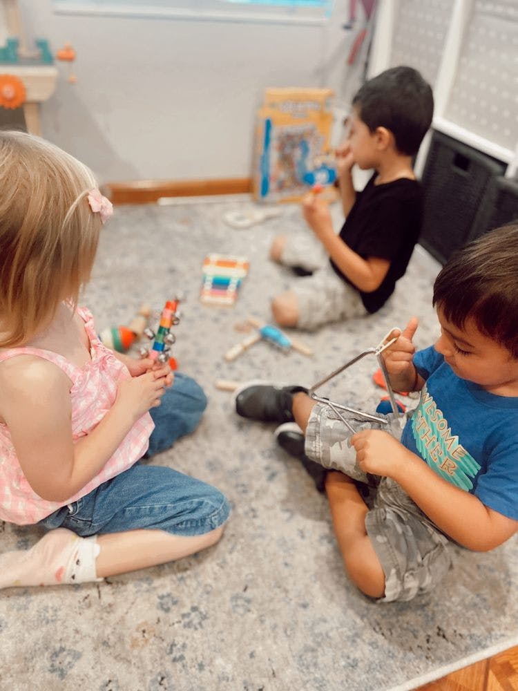 Three children sitting on a rug playing with toys