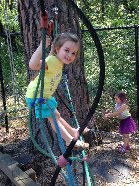 Child climbing on a rope structure, another child in the background