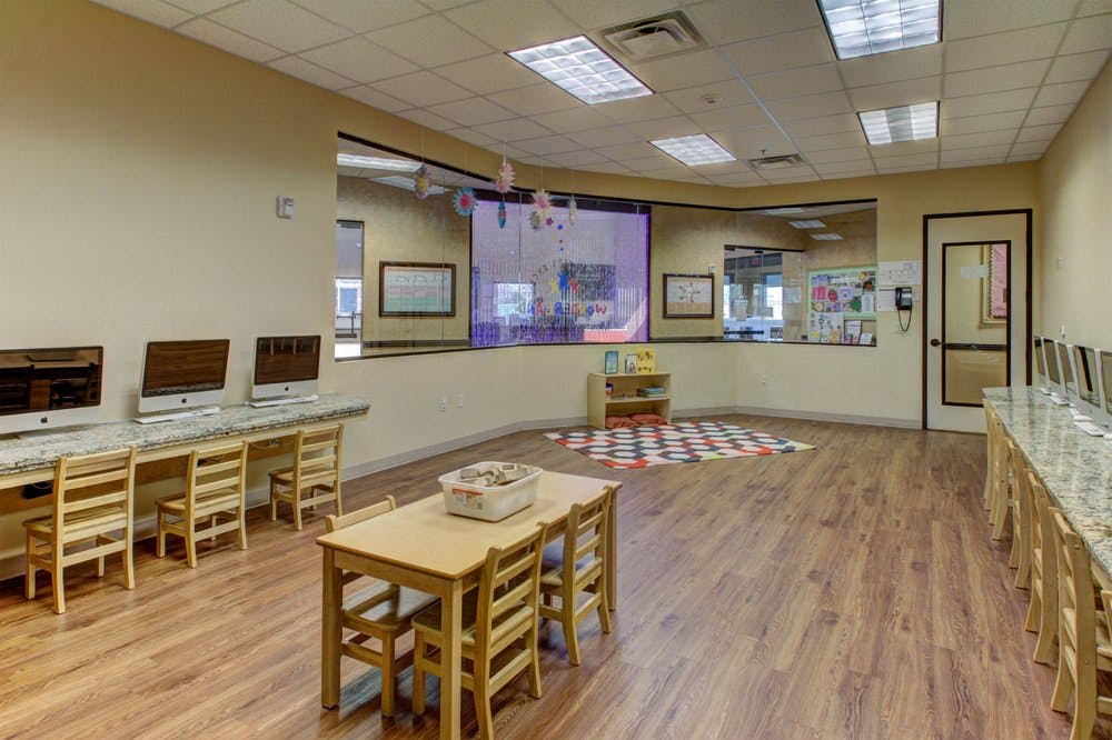 Classroom with computers on desks and small tables with chairs