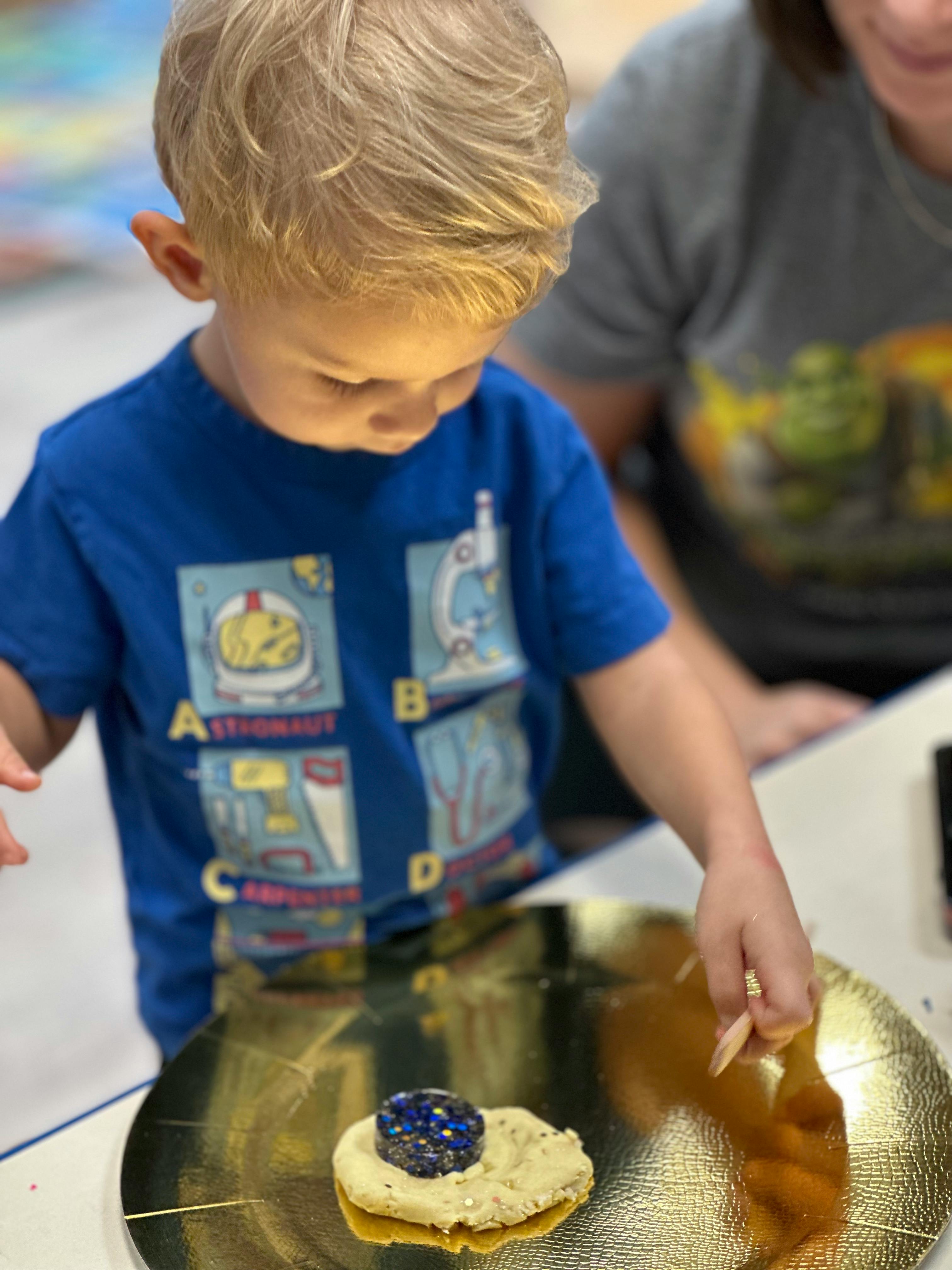 Child decorating a cookie with a blue gem