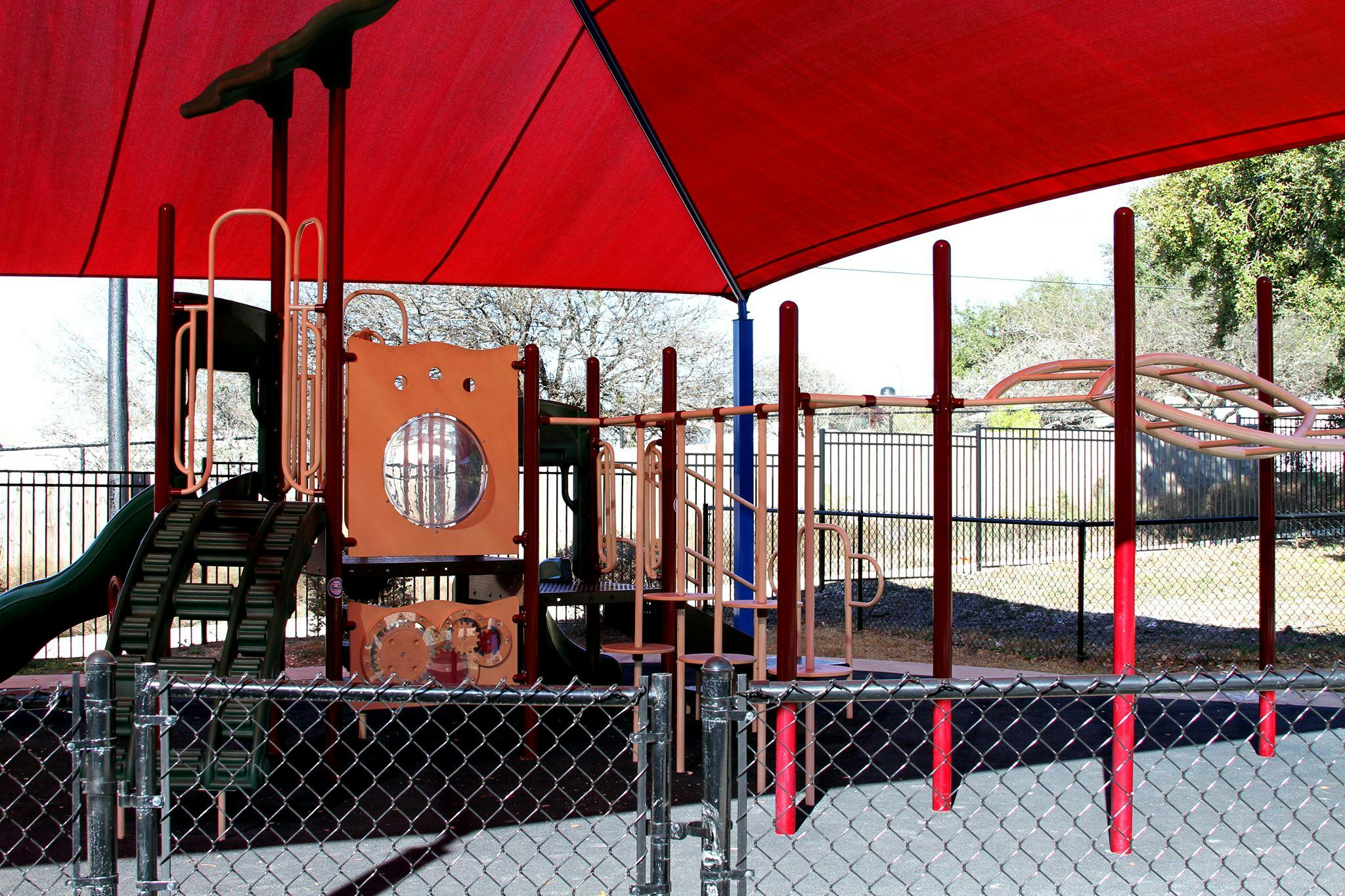 Playground with slides, climbing structures, and red shade canopy