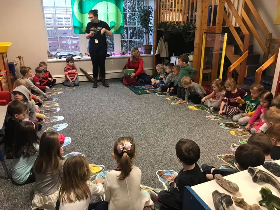 Adults and children sitting in a circle on the floor in a classroom