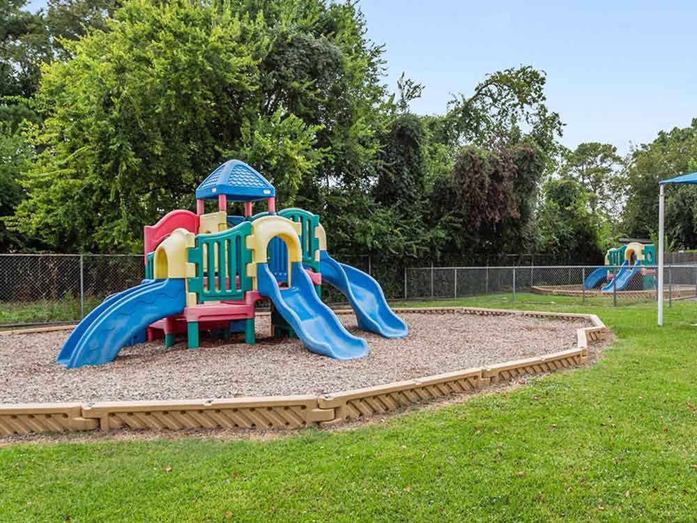 Colorful playground structure with multiple slides on a wood chip surface