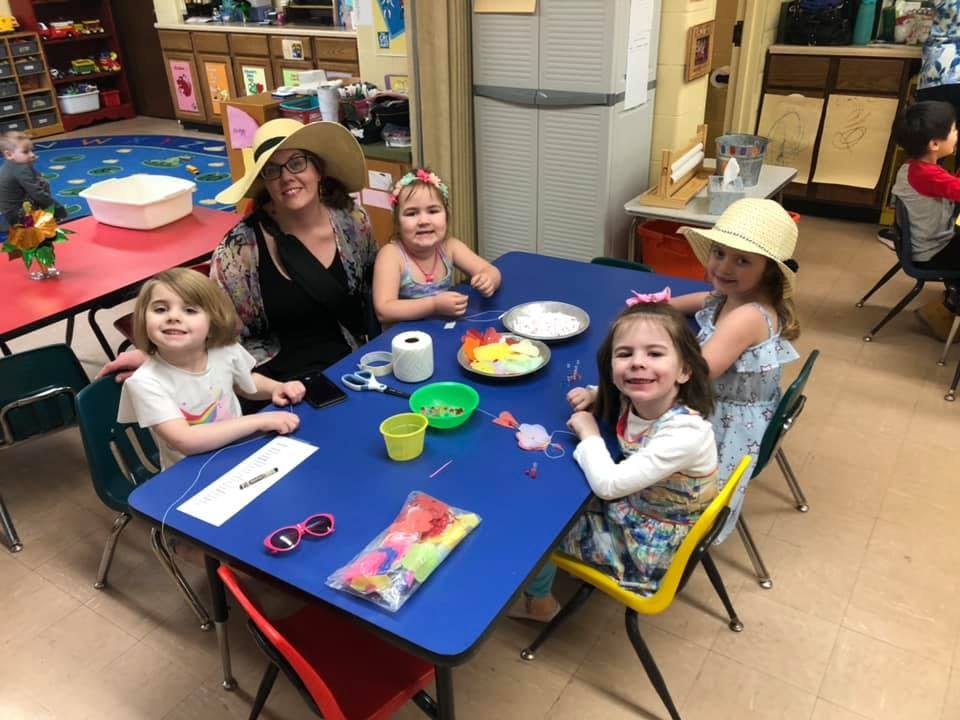 Adult and four children sitting at a blue table in a classroom
