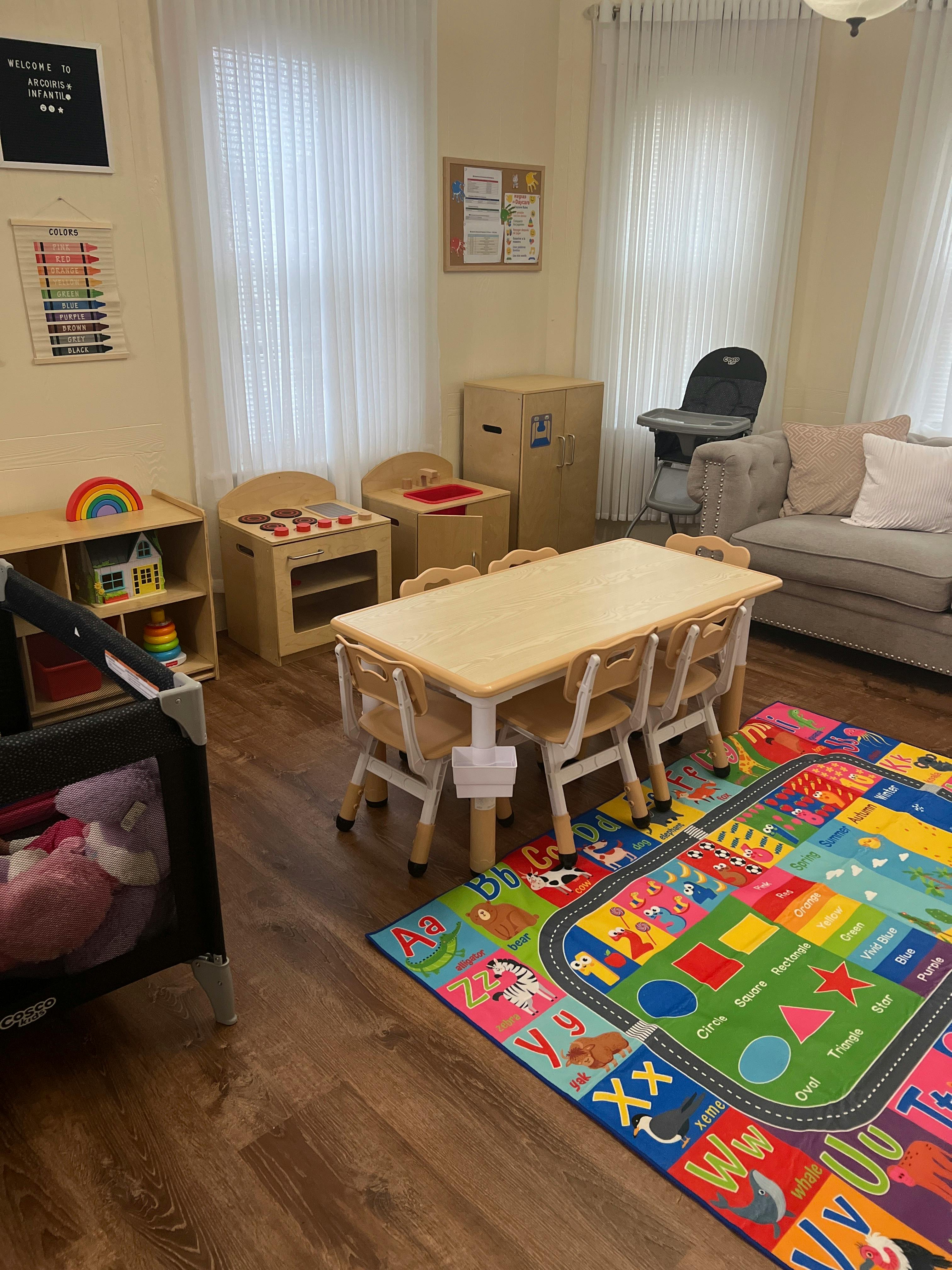 Children's play area with small table and chairs, play kitchen, and colorful rug