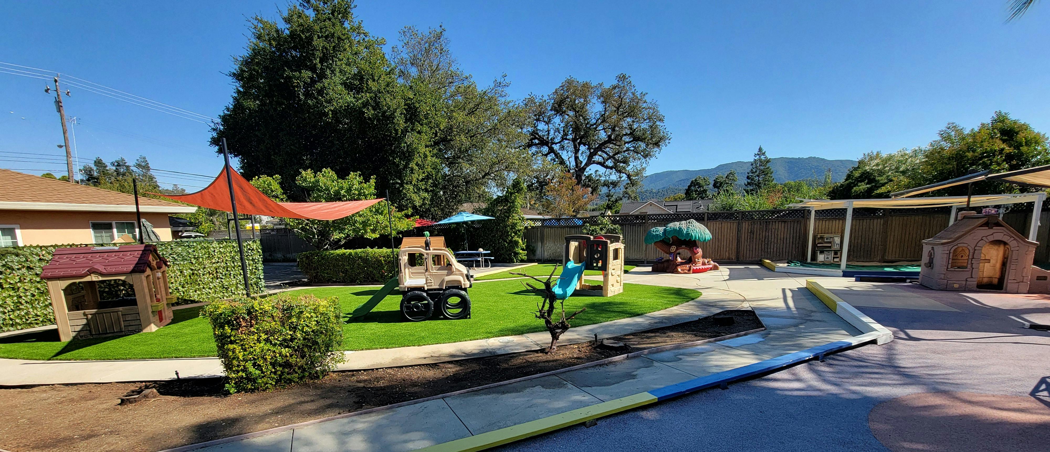 Outdoor play area with various play structures and green grass
