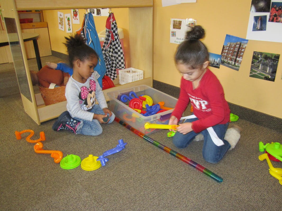 Two children playing with colorful toys on the floor