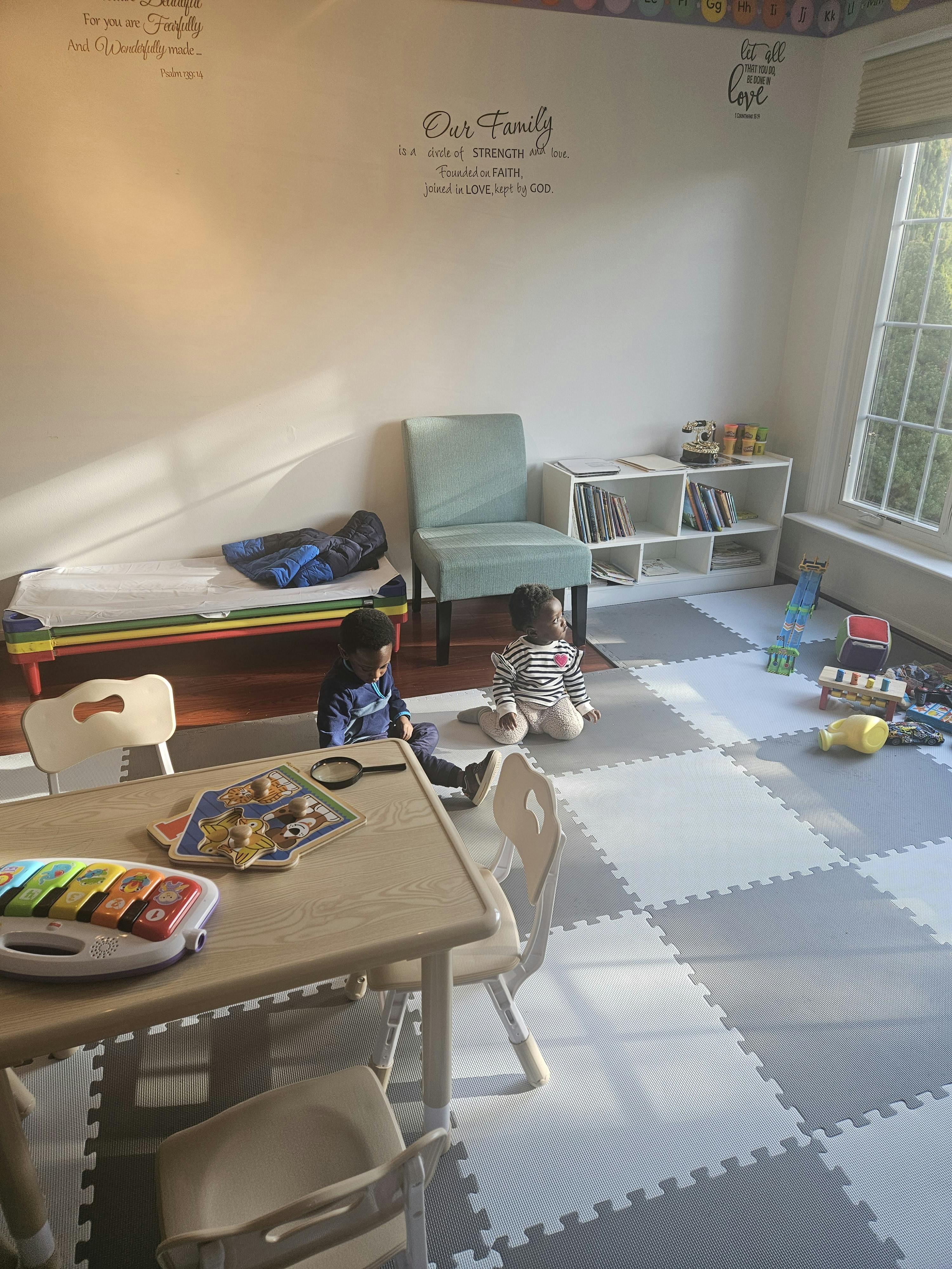 Two children playing on a checkered floor in a room with a table and toys