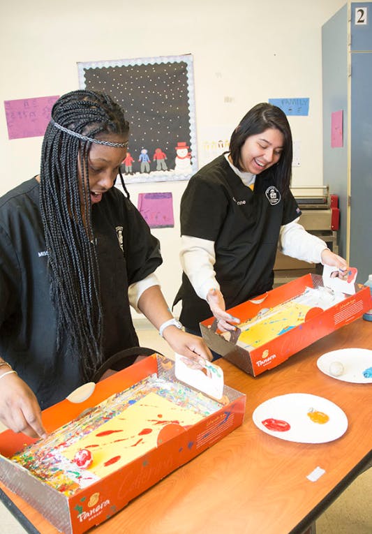 Two people decorating cakes in boxes