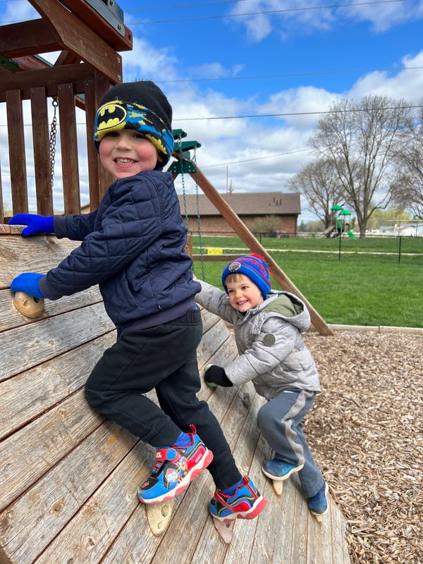 Two children climbing a wooden play structure