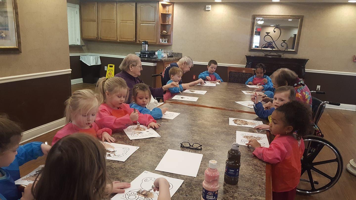 Adults and children sitting around a table drawing