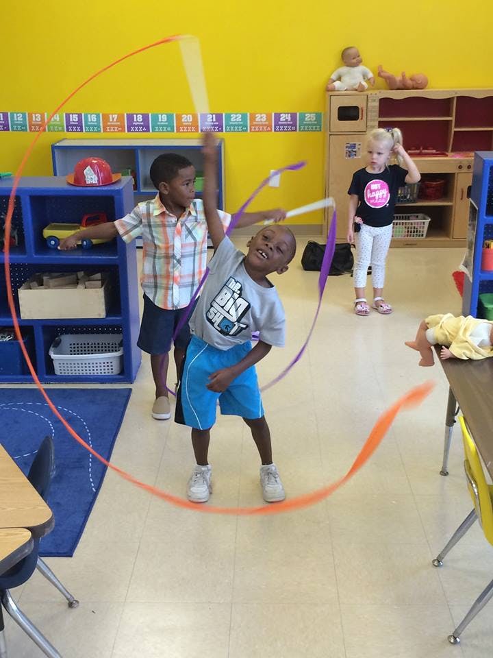 Child playing with a ribbon wand in a classroom