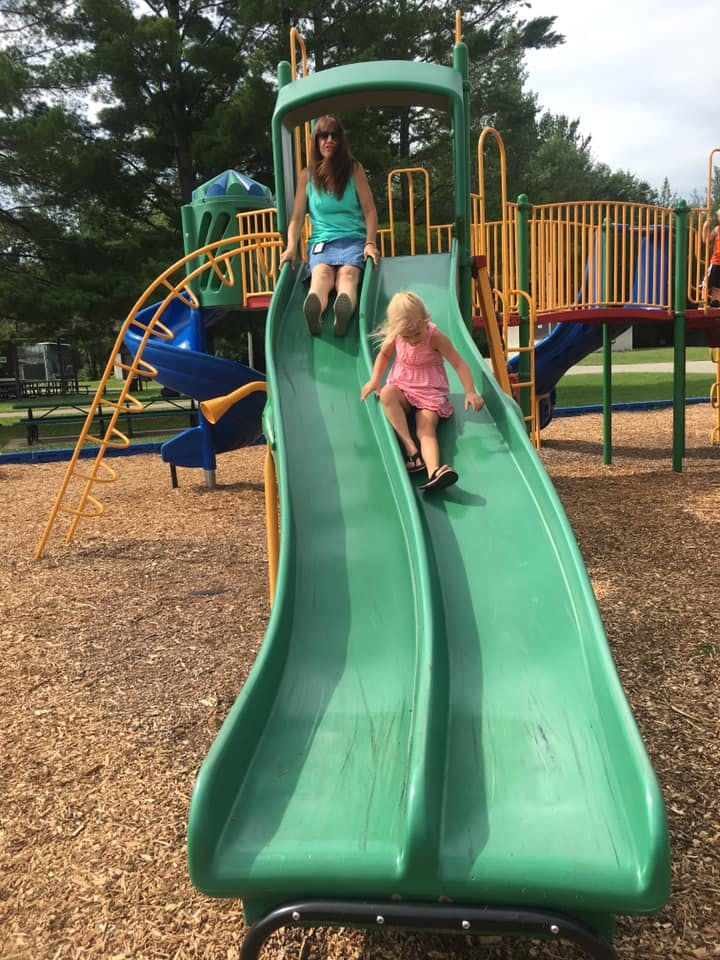 Person and child on a green playground slide