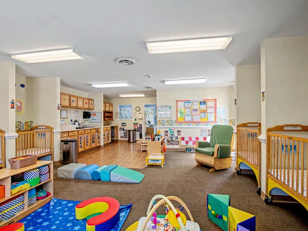 daycare or nursery room with cribs, play mats, and a kitchen area