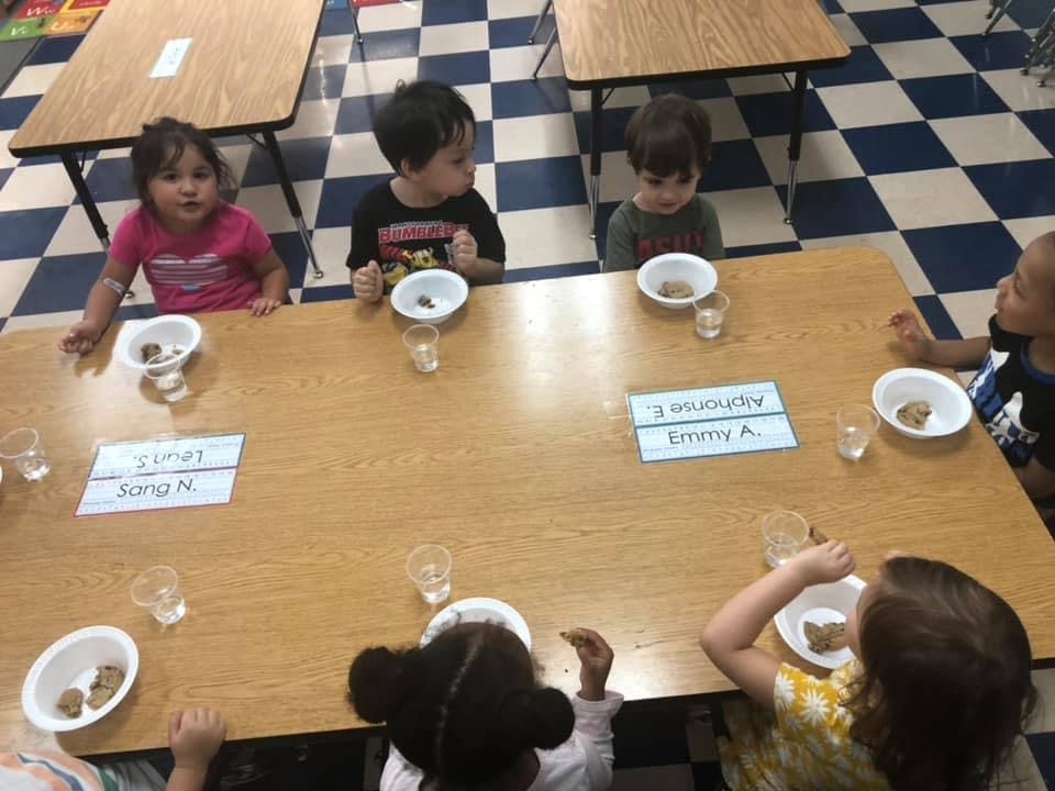 Children sitting at a table with bowls and cups