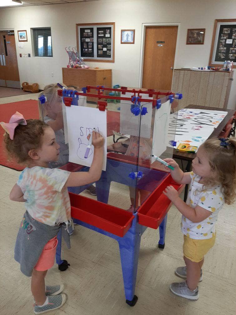 Two children drawing on an easel
