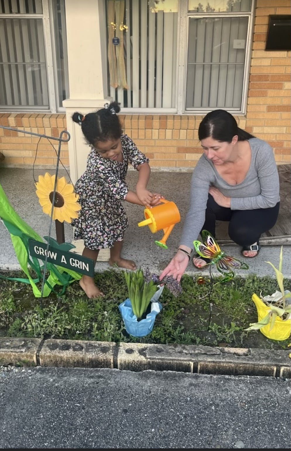 Child watering a plant with a person