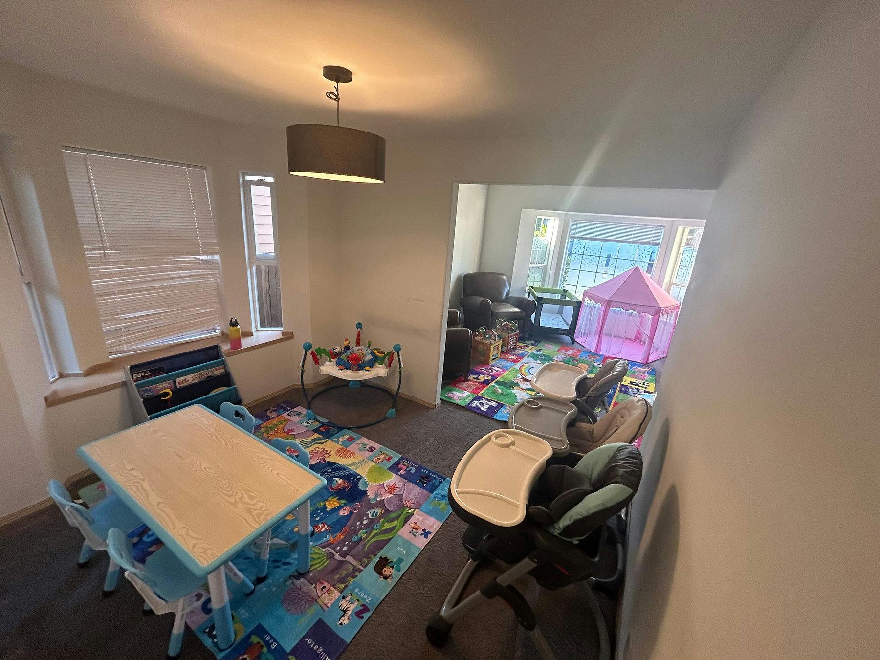 Children's play area with small table and chairs, play mat, and baby activity center