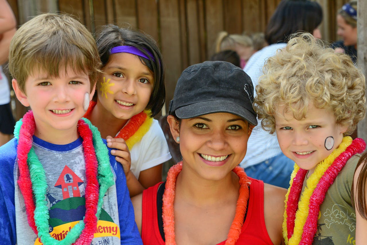 Four people, including three children, wearing leis and face paint