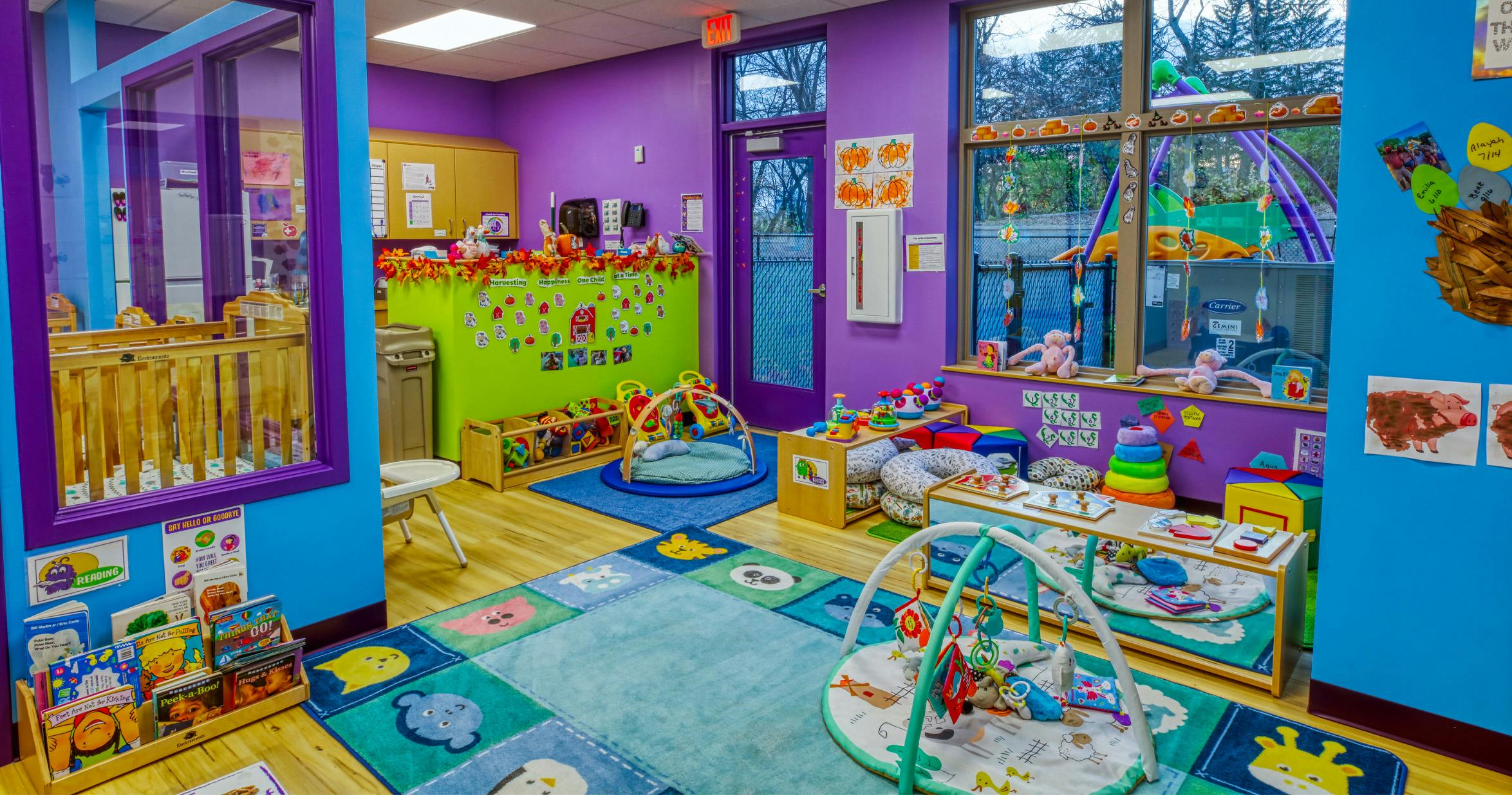 Playroom with colorful walls and rug, cribs, and various infant toys and activity mats