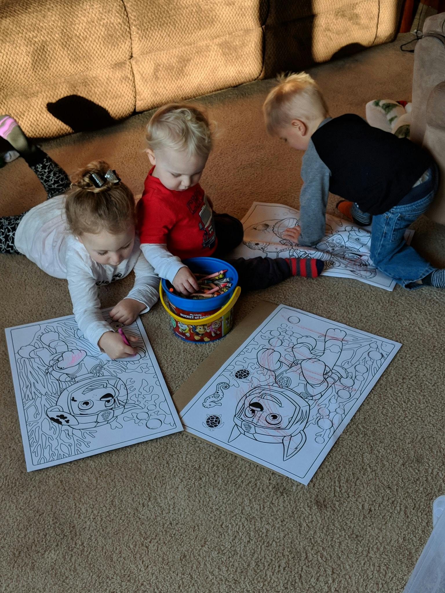 Three children coloring on the floor