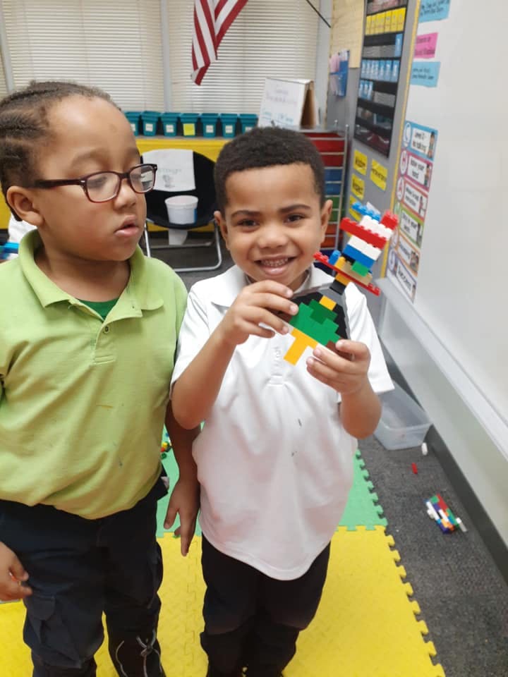 Two children, one holding a colorful block creation