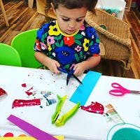 Child cutting paper with scissors at a table