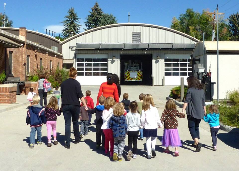 Adults and children walking toward a building with garage doors