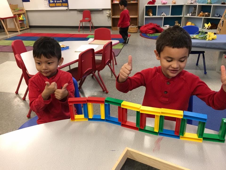 Two children playing with colorful building blocks in a classroom