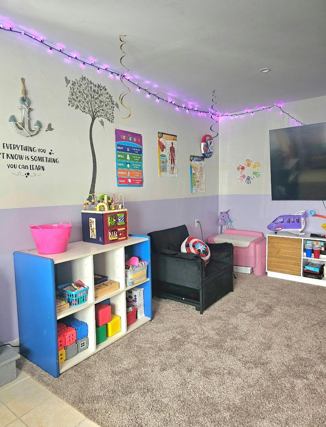 Children's room with toys, educational posters, and string lights