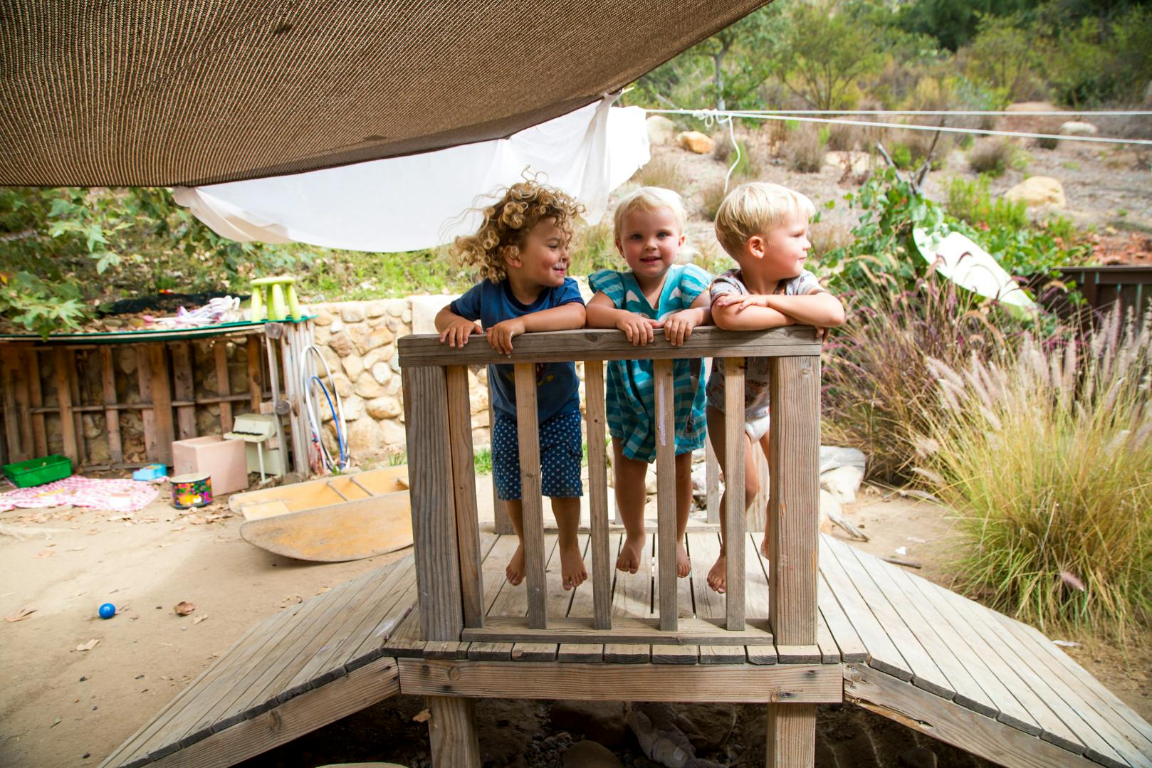 Three children standing on a wooden play structure