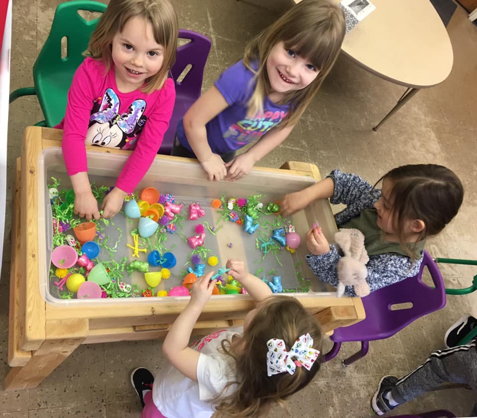 Children playing with toys in a sensory table