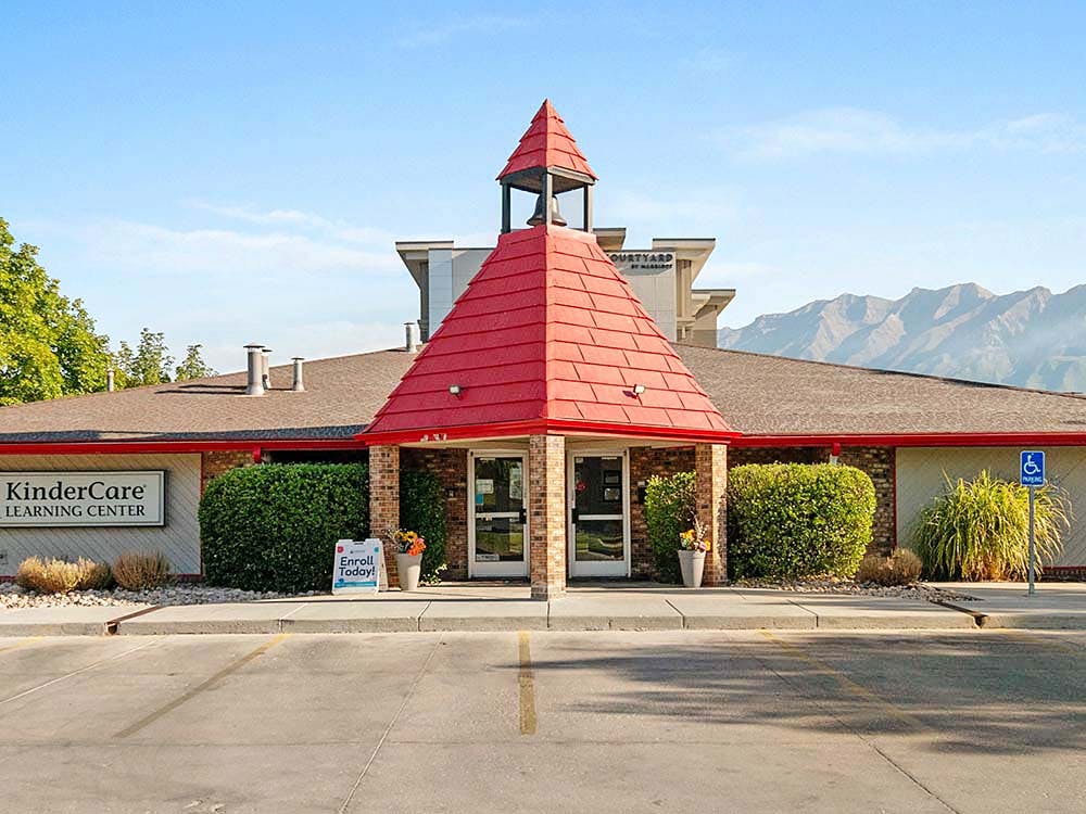 KinderCare Learning Center building with red roof, brick facade, and landscaping