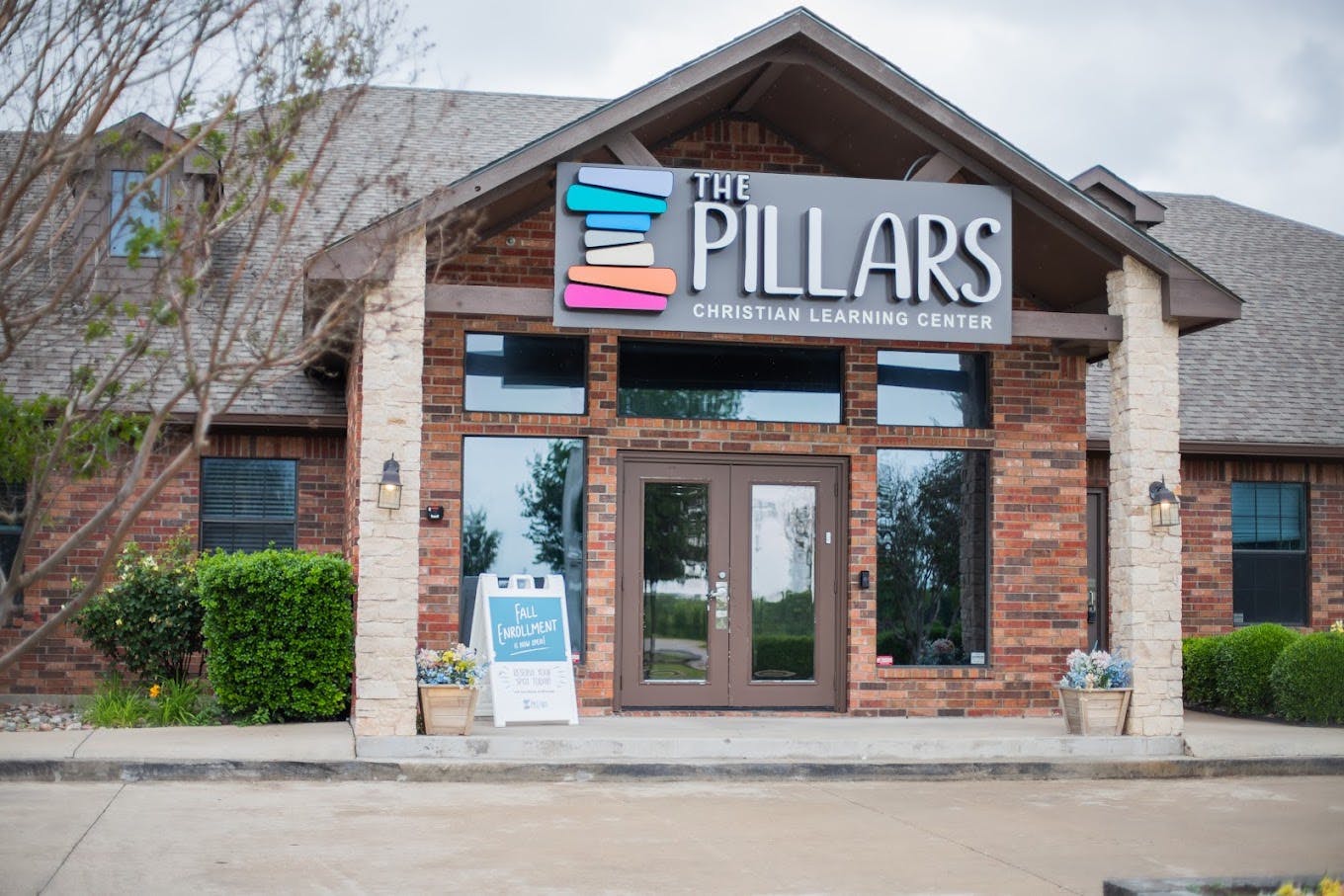 Exterior of The Pillars Christian Learning Center with fall enrollment sign