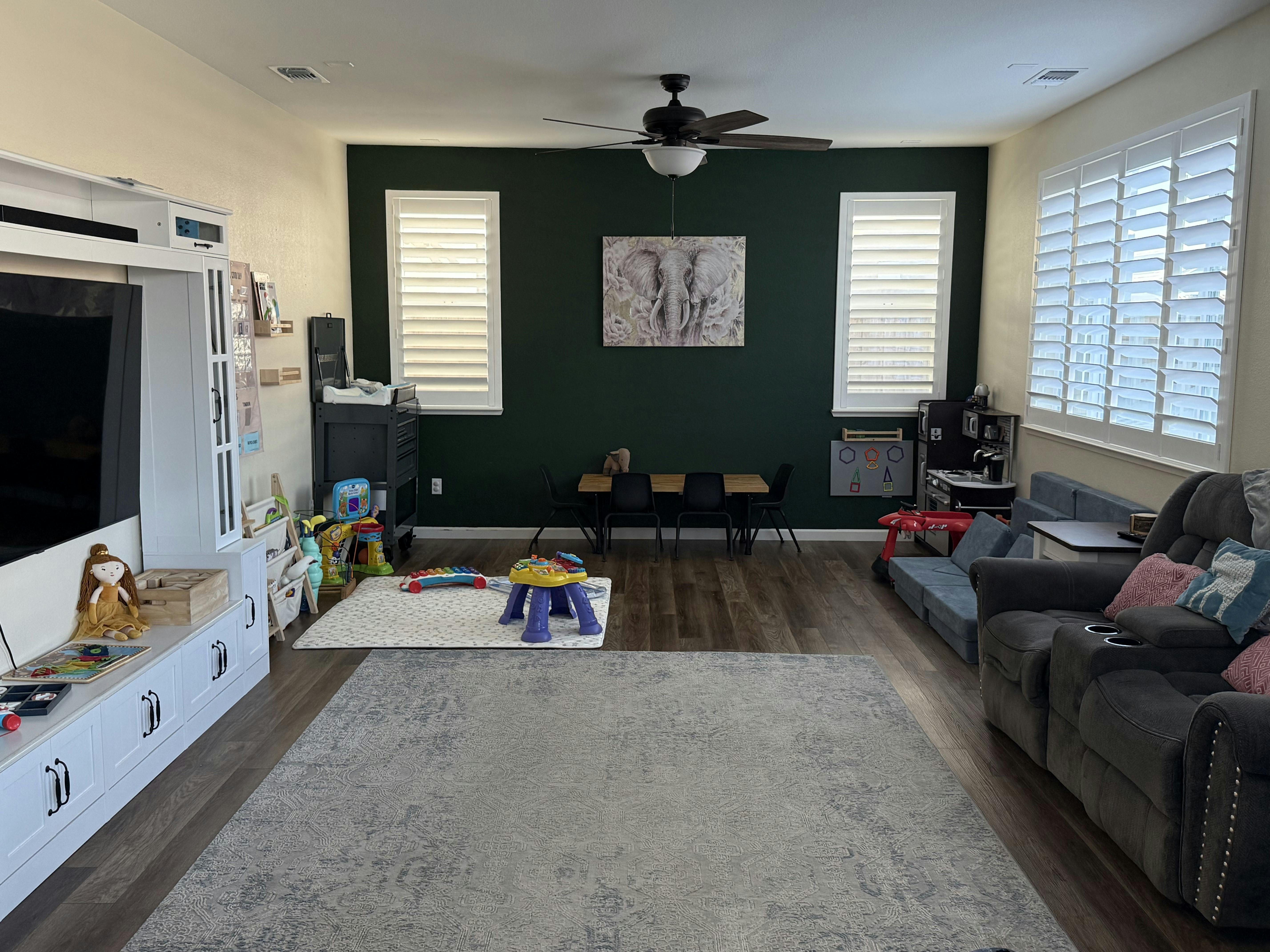 Living room with a dark green accent wall, white entertainment center, and gray rug