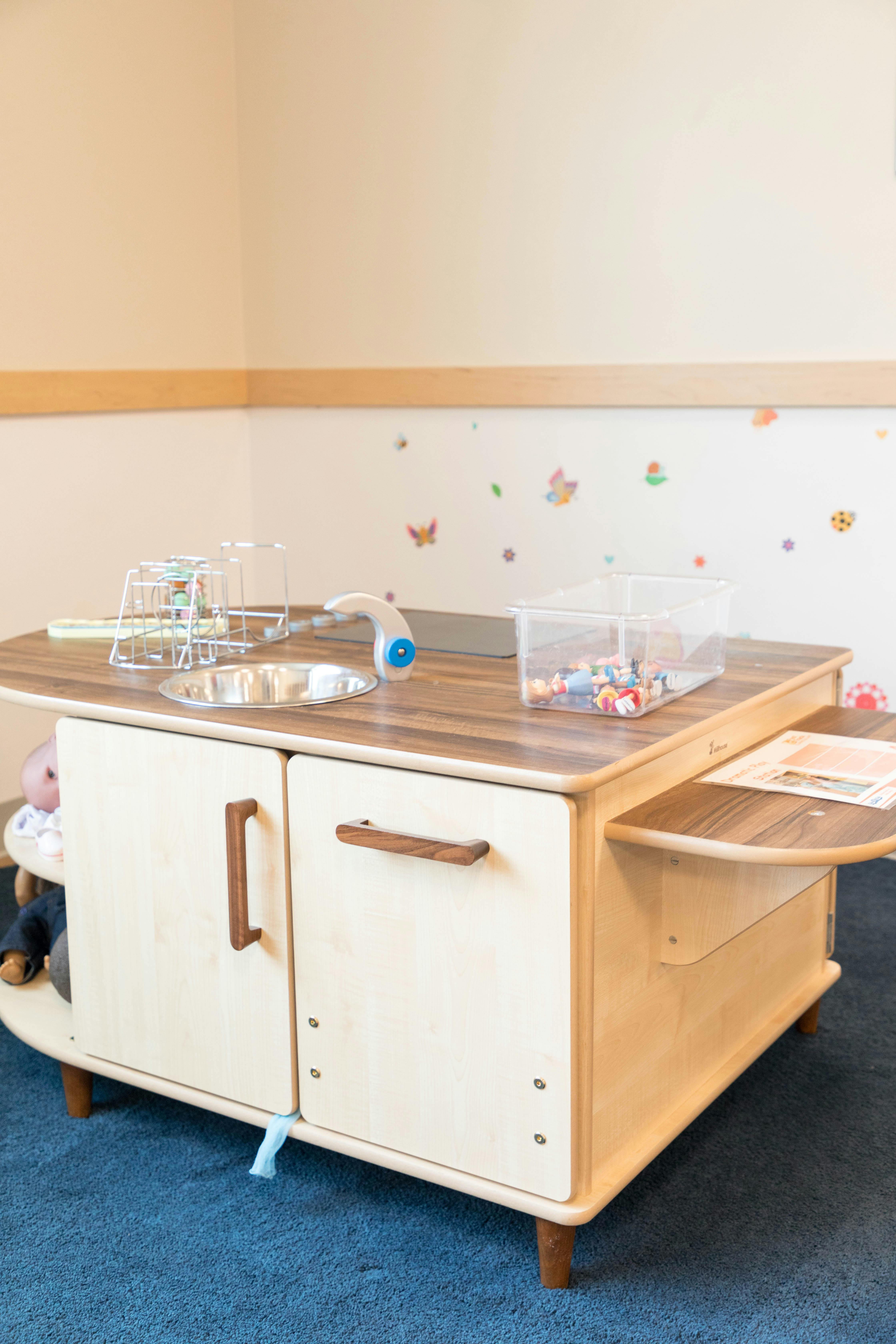 Play kitchen with sink, faucet, and clear container of small toys