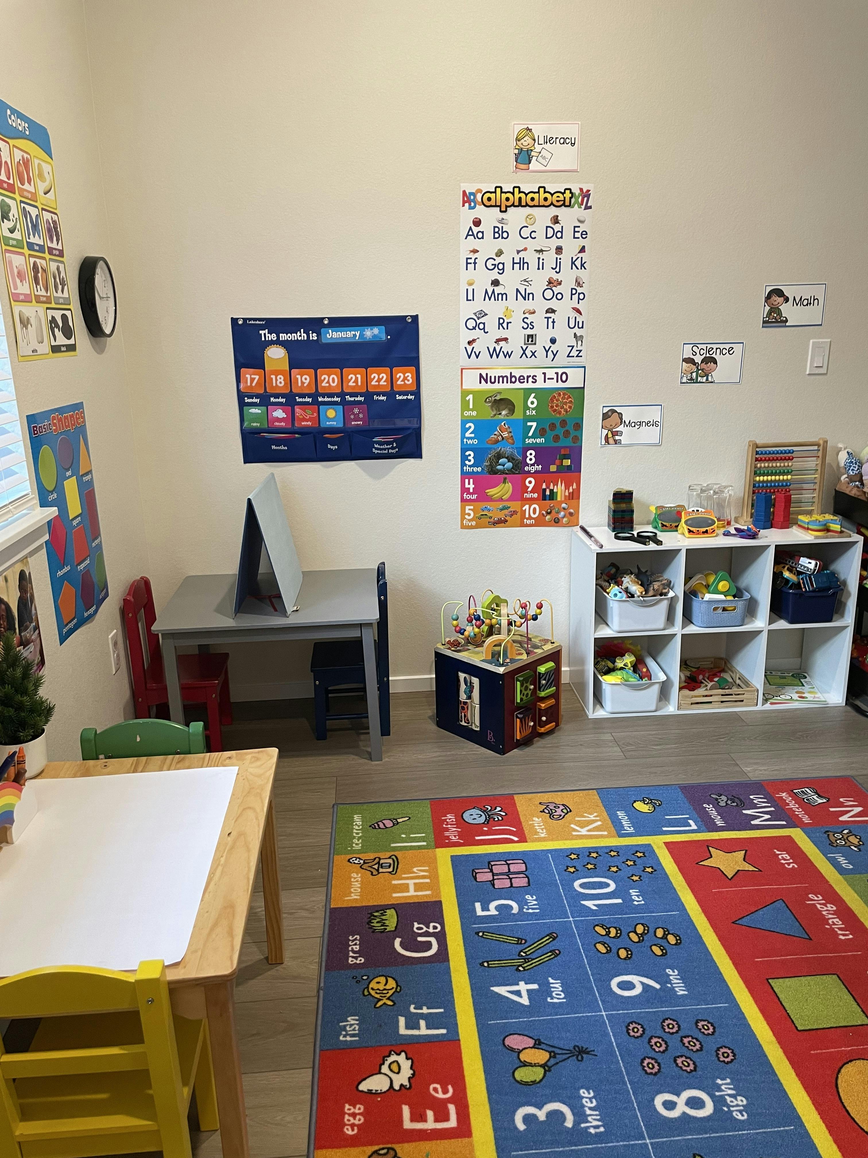 Classroom with alphabet and number charts, tables, chairs, and storage shelves