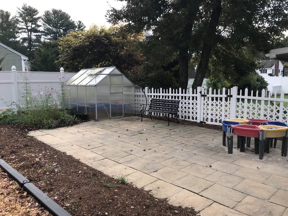 Greenhouse, bench, and colorful play tables on a patio