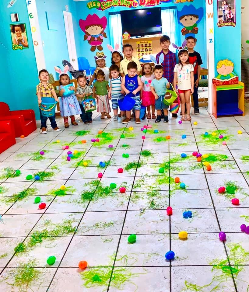 Group of children standing in a room with colorful eggs on the floor