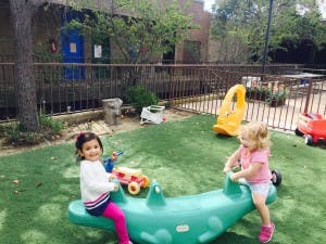 Two children on a green seesaw toy