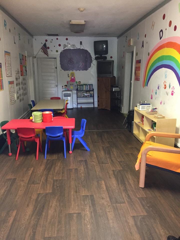 Classroom with small tables and chairs, rainbow mural on wall