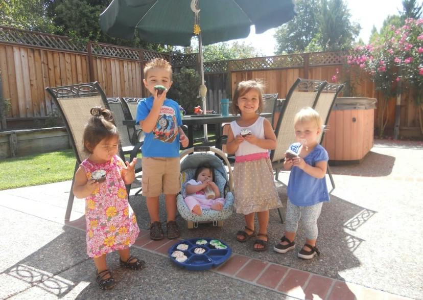 Group of children eating cupcakes outdoors on a patio