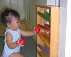 Child playing with red balls and a wooden toy