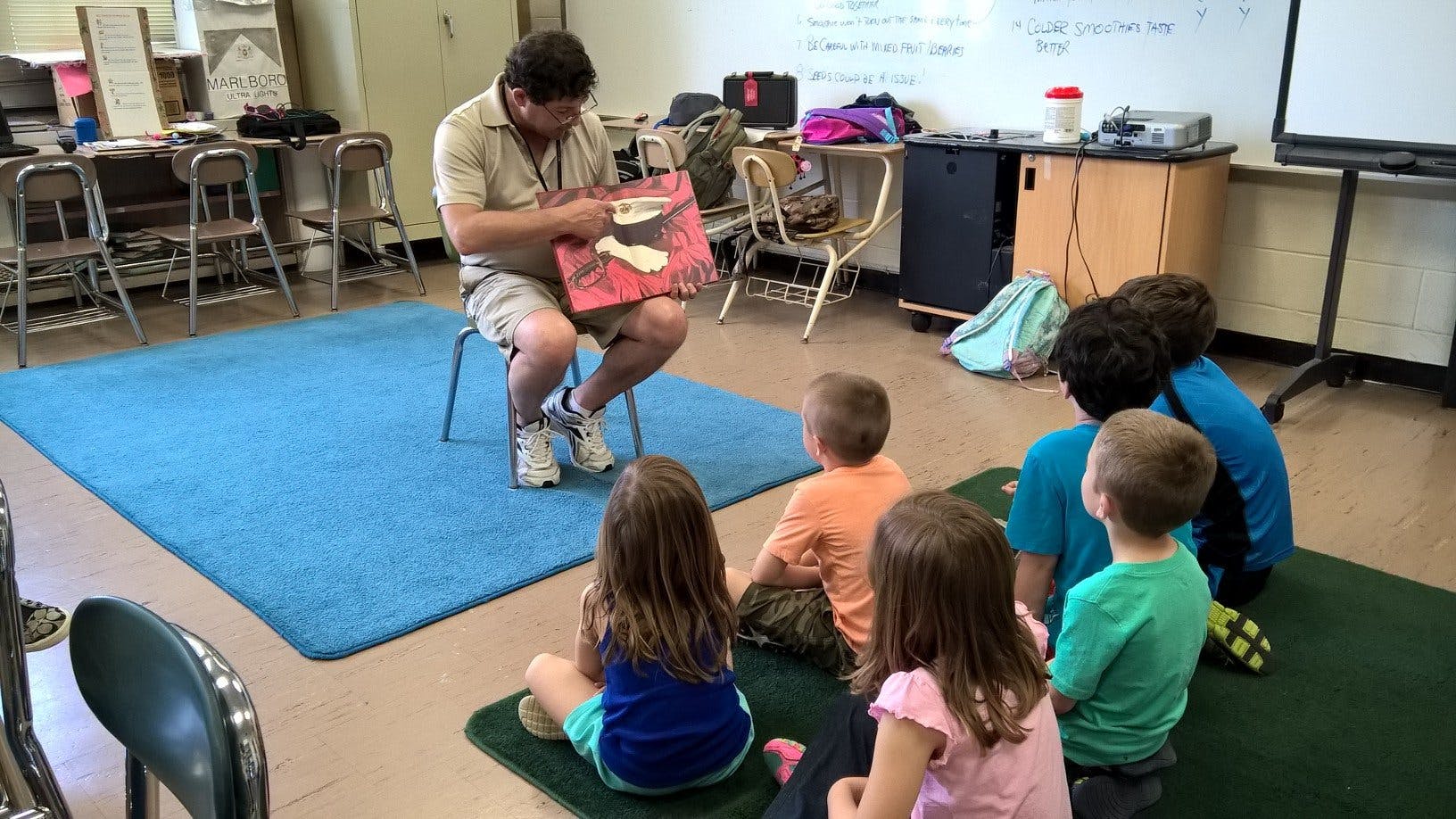 Person reading a book to children in a classroom