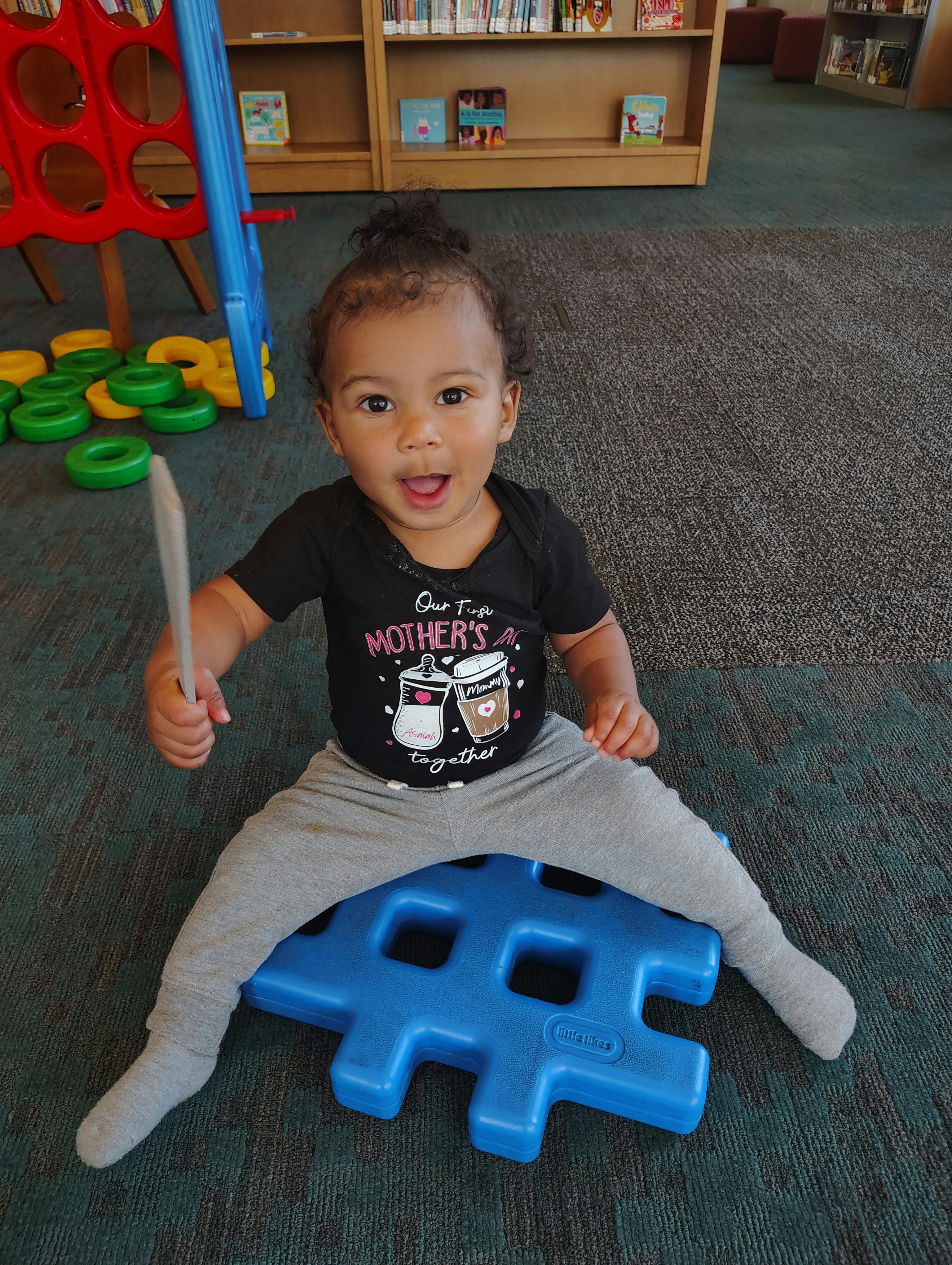 Child lying on their back on a rug with their legs raised, holding a toy