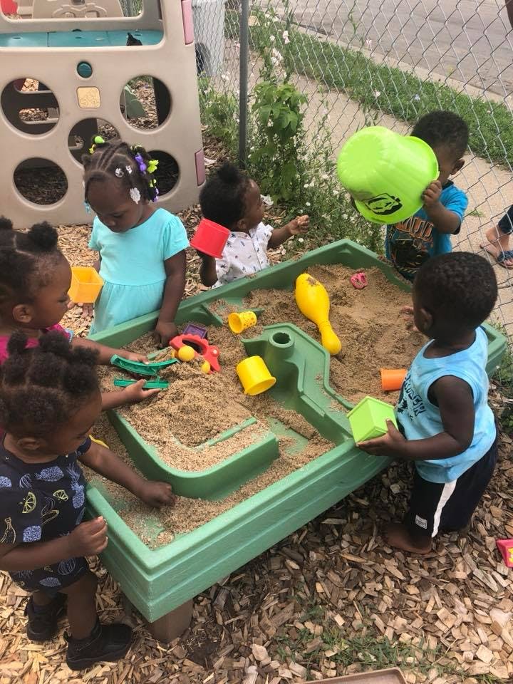Children playing in a sandbox with toys