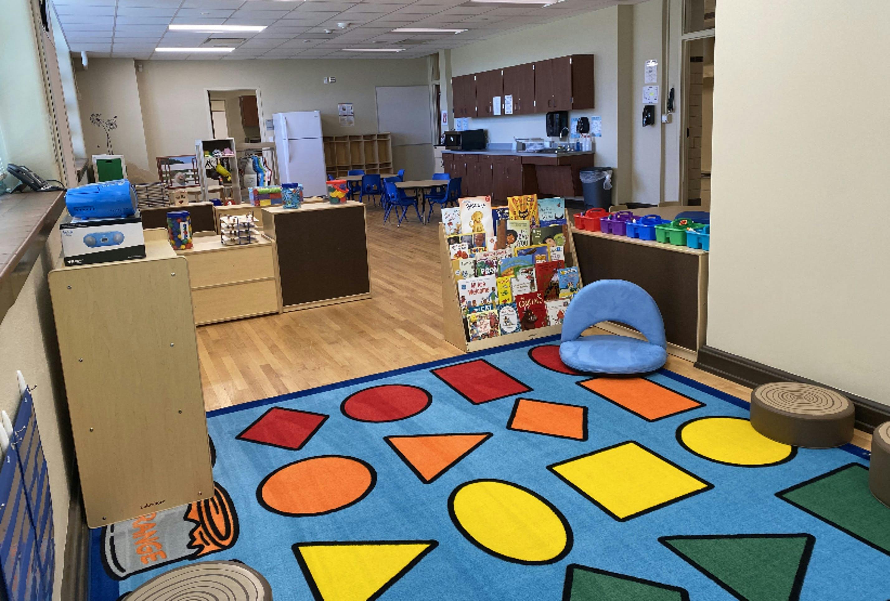 Classroom with a blue rug featuring colorful geometric shapes